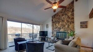 Ein Wohnzimmer mit Steinswand, Deckenventilator, Fernseher und einer Terrasse mit Grill.