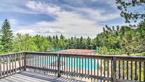 A wooden deck overlooking a swimming pool with a view of a forested area. - Renovated Ski-in/ski-out Peru Condo at Bromley Mtn (Peru)