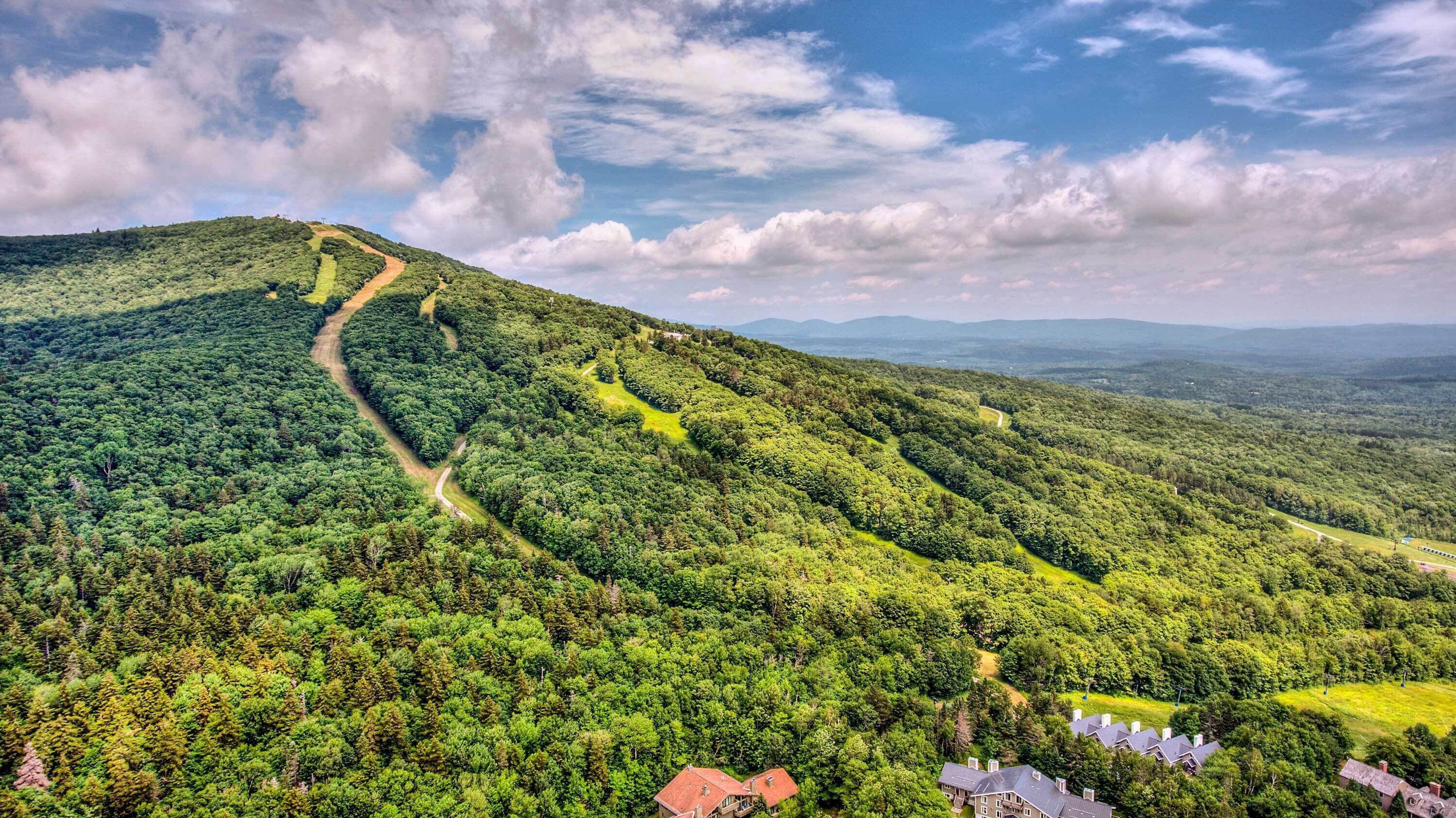 A mountainous landscape with a winding road and scattered buildings.