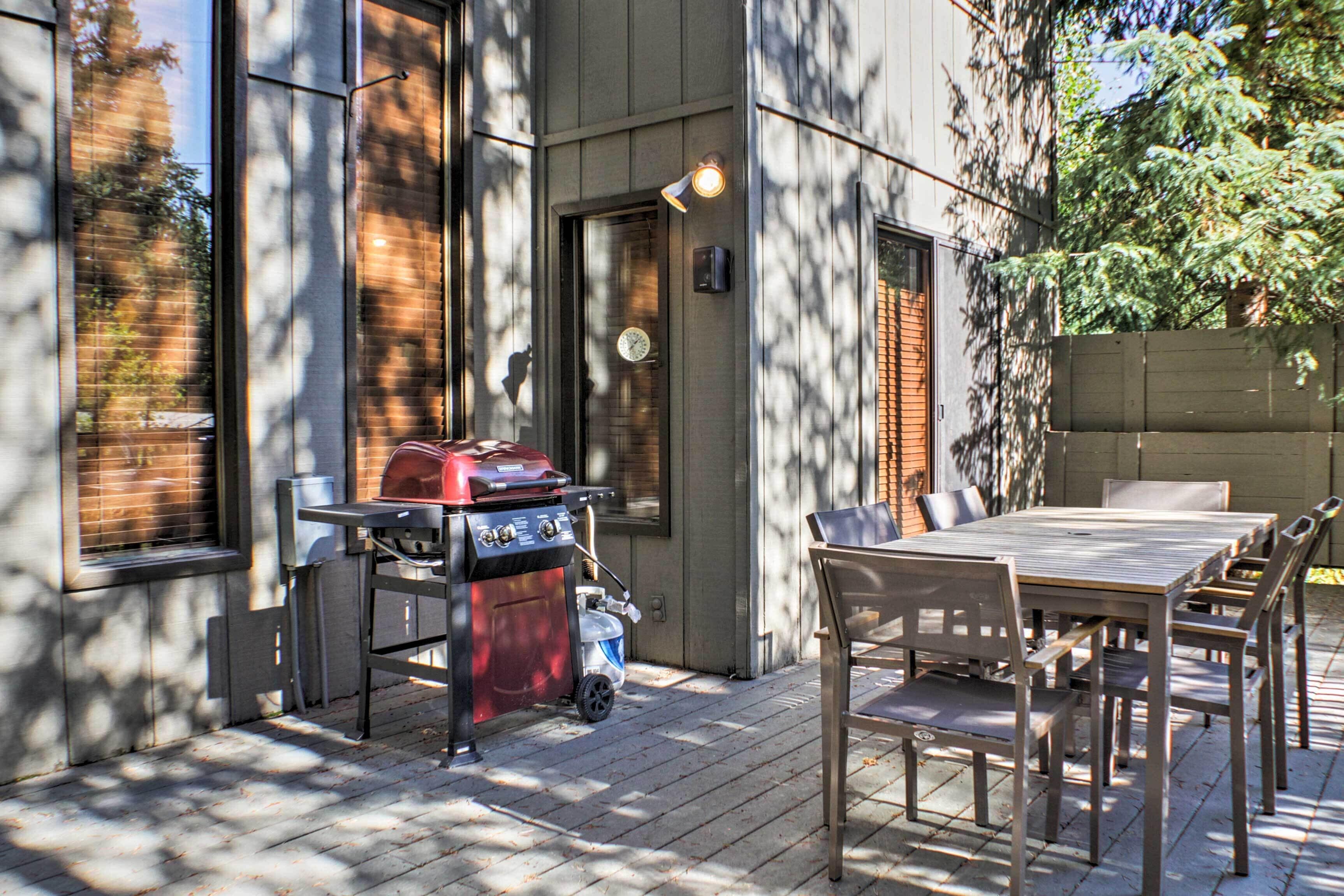 An outdoor patio with a grill, a table, and chairs.