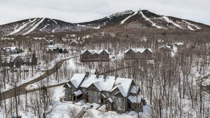 A snow-covered residential area with houses and a mountain in the background. - Ski-in Resort Family Condo w/ Deck at Jay Peak! (North Troy)