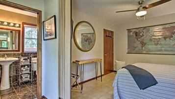 A bedroom with a bed, a desk, a chair, a mirror, a sink, and a map on the wall.