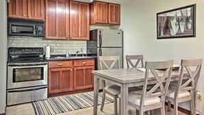A kitchen with wooden cabinets, stainless steel appliances, and a dining table with chairs. - Pet-friendly Wabasha Studio: Boat, Ski & Explore! (Wabasha)