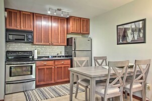 Una cocina con armarios de madera, electrodomésticos de acero inoxidable y una mesa de comedor con sillas.