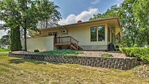 A single-story house with a front porch, a small staircase leading to a deck, and a stone retaining wall. - Pet-friendly Wabasha Studio: Boat, Ski & Explore! (Wabasha)