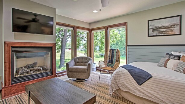 A bedroom with a bed, a chair, a table, a fireplace, and a ceiling fan. - Pet-friendly Wabasha Studio: Boat, Ski & Explore! (Wabasha)
