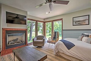 A bedroom with a bed, a chair, a table, a fireplace, and a ceiling fan. - Pet-friendly Wabasha Studio: Boat, Ski & Explore! (Wabasha)