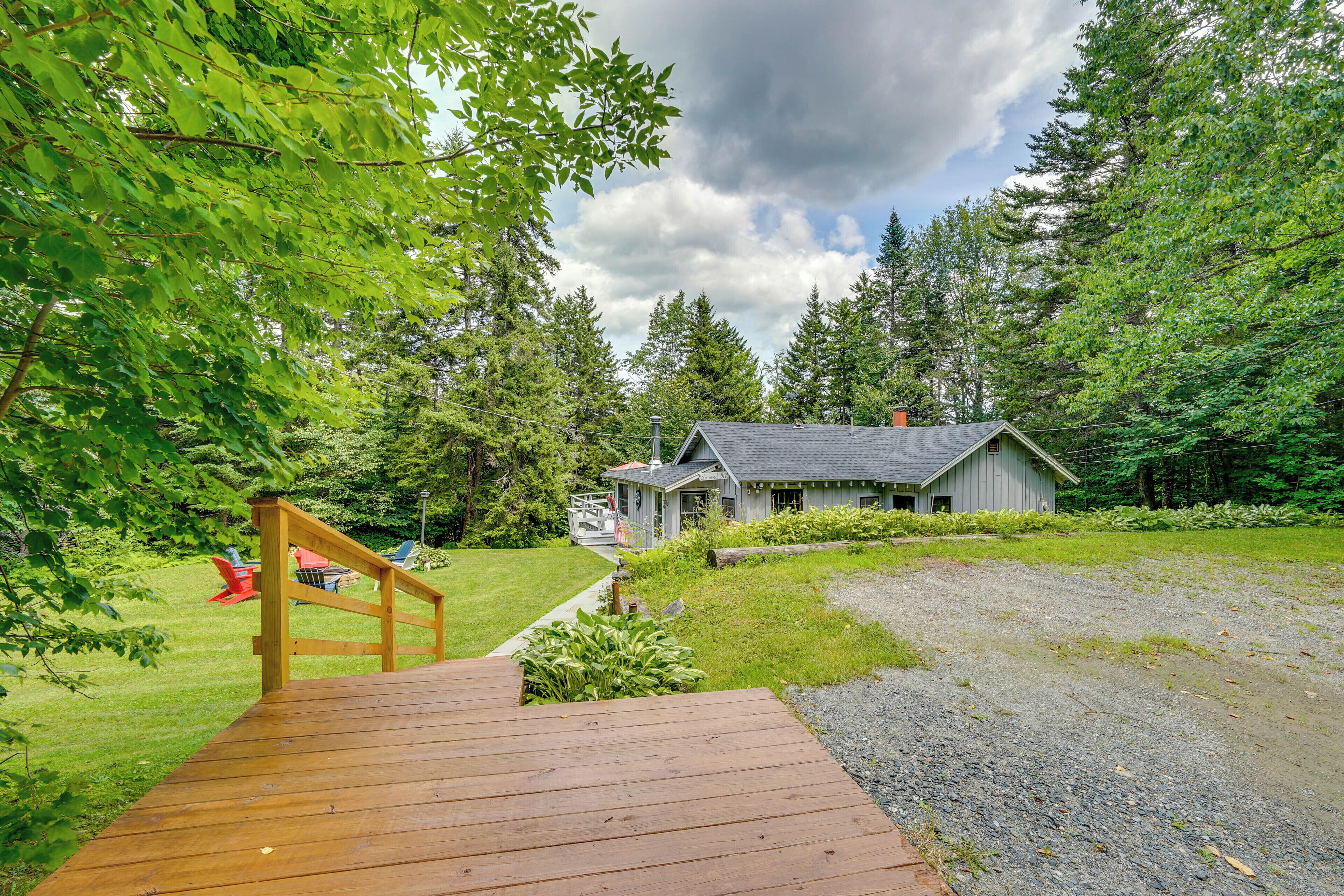 A wooden deck leading to a cabin surrounded by lush greenery and trees.