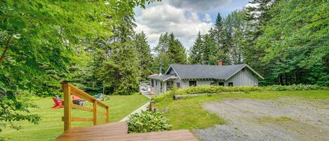 A wooden deck leading to a cabin surrounded by lush greenery and trees.