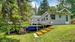 Ein Haus mit einer Terrasse, umgeben von Bäumen und einer sanften Grünfläche.