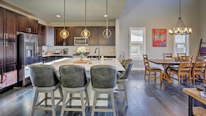 A modern kitchen with dark wood cabinets, stainless steel appliances, and a central island with bar stools. - 3 Mi to Granby Ranch: Expansive Granby Retreat! (Granby)