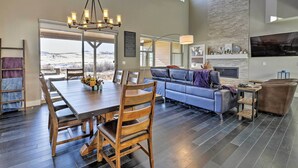 A spacious living area with a dining table, chairs, a sofa, and a TV mounted on the wall. - 3 Mi to Granby Ranch: Expansive Granby Retreat! (Granby)