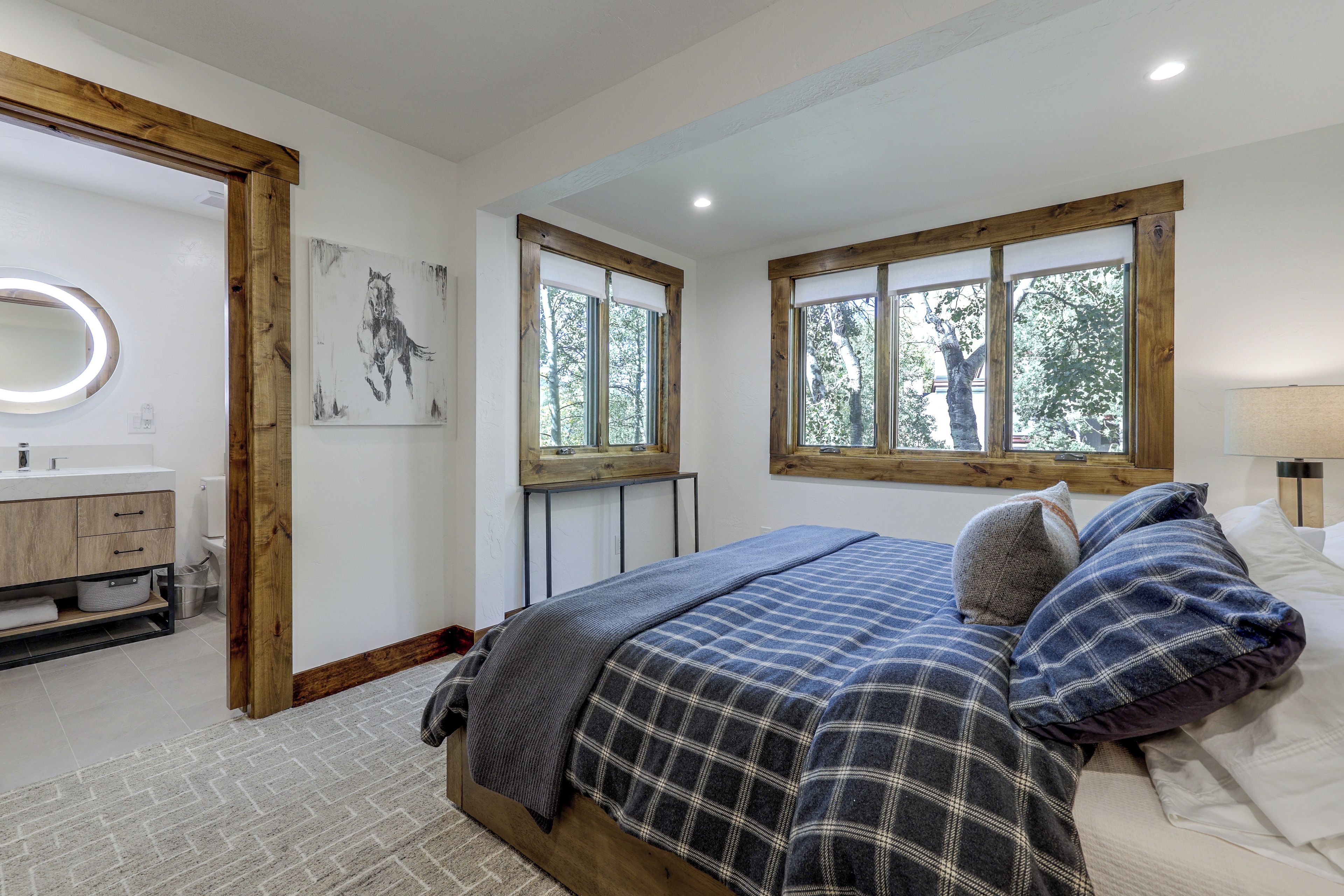 A bedroom with a bed, a window, a bedside table, and a mirror.