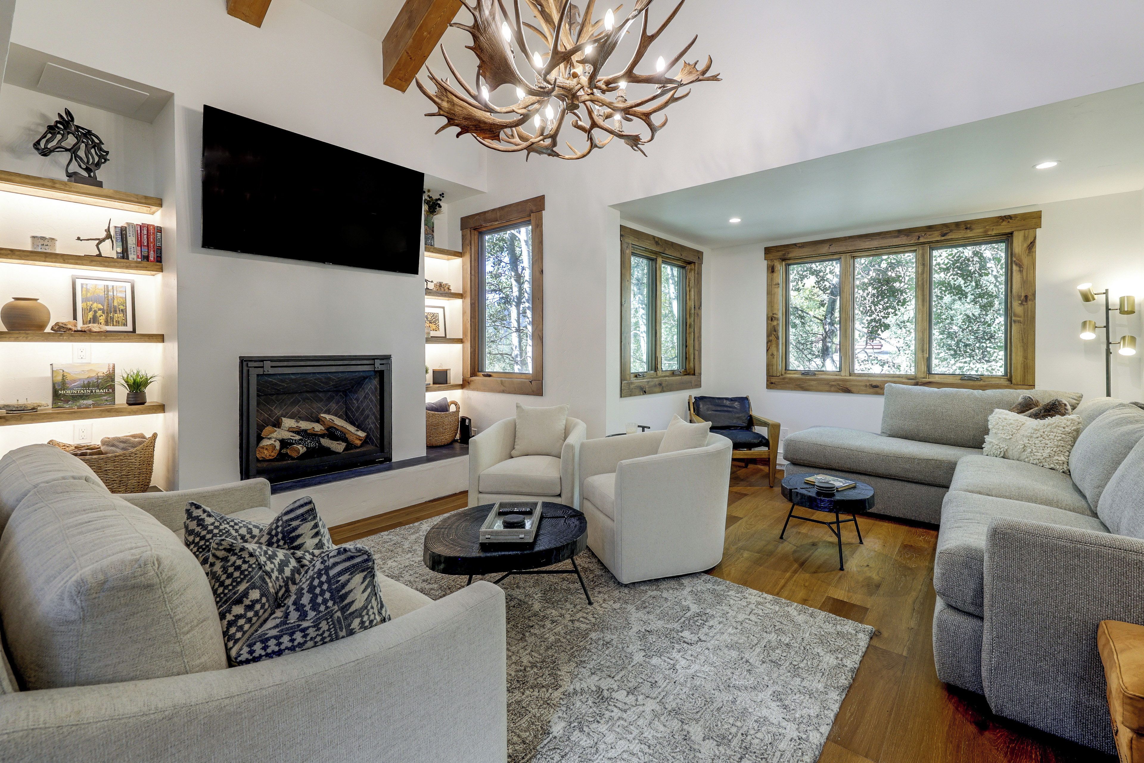 A modern living room with a fireplace, comfortable seating, and large windows.