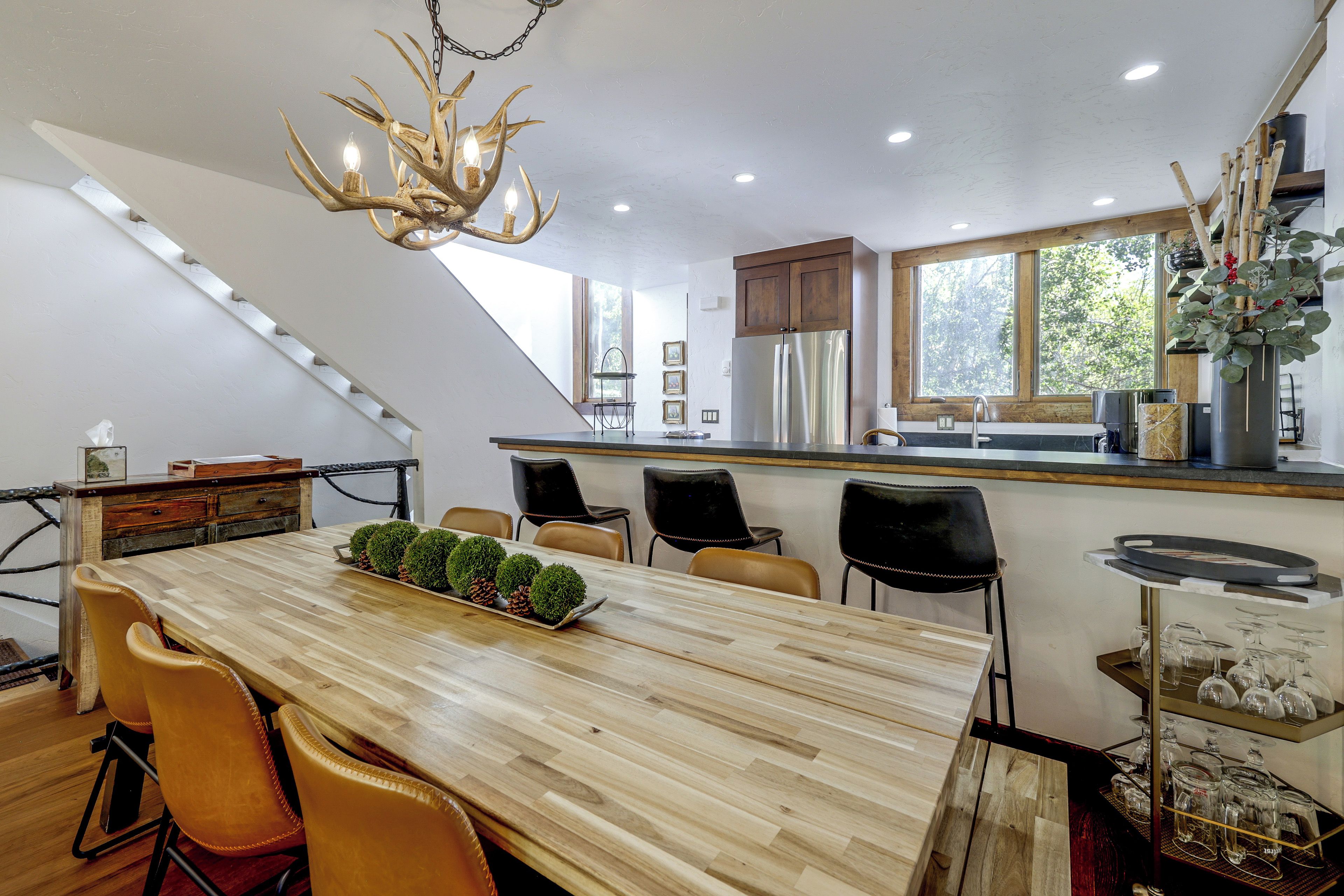 A modern kitchen with a central island, dining chairs, and a chandelier.