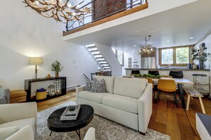 A spacious living area with a high ceiling, a staircase, a dining area, and a kitchen. - Newly Renovated Vail Home - Walk to Booth Falls Tr (Vail)