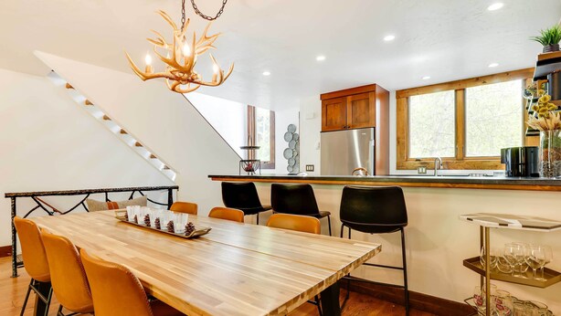 A modern kitchen with a large island, wooden flooring, and a chandelier. - Elegant Vail Home - Walk to Booth Falls Trail (Vail)