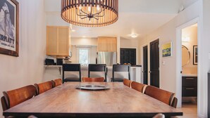 Ein Essbereich mit einem Holztisch und Stühlen, einer Chandelier und Holzschränken.