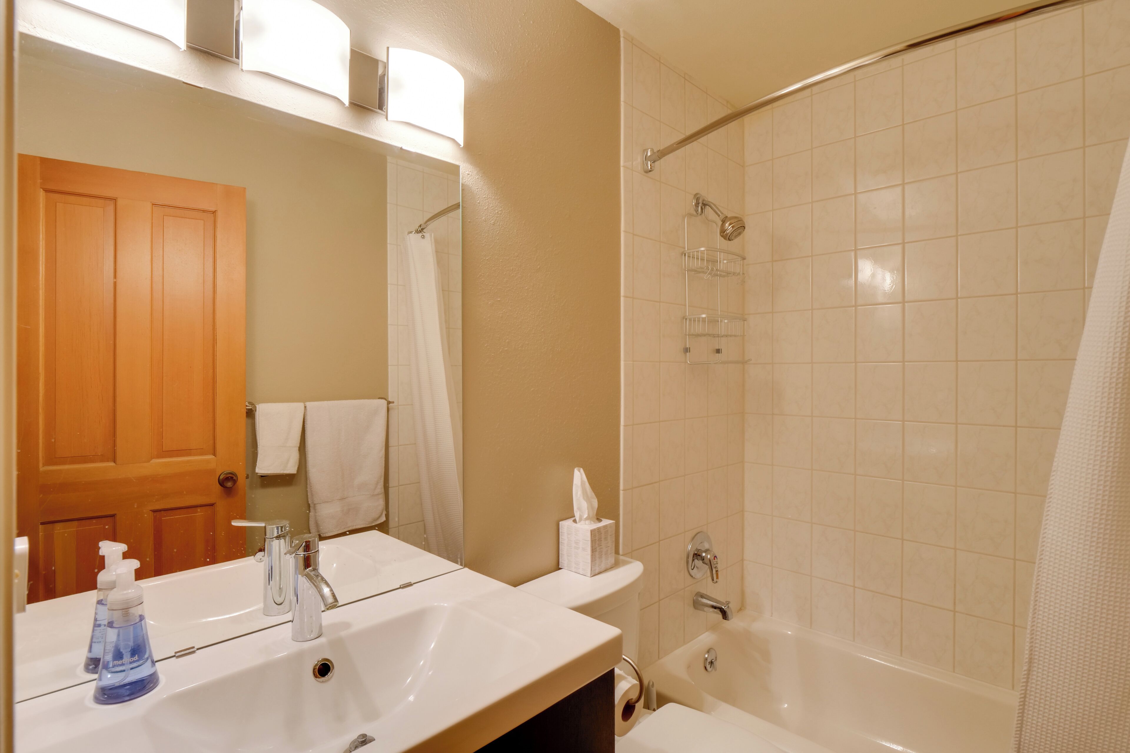 A bathroom with a sink, mirror, towel rack, and shower area.