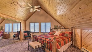 A bedroom with a sloped ceiling, a wooden bed frame, a quilt, a chair, and a bedside table. - Questa Home w/ Views - 13 Mi to Red River Skiing! (Questa)