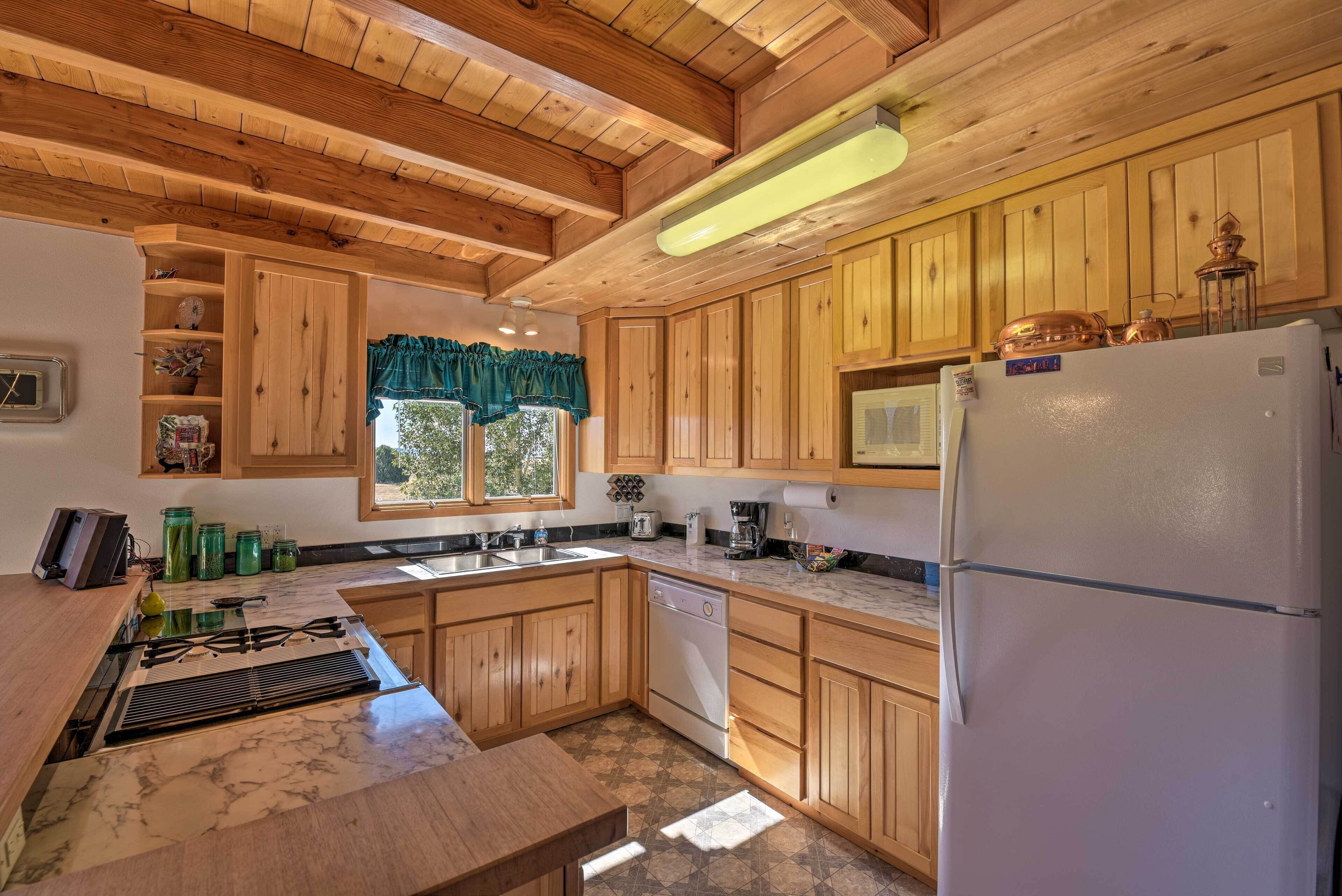 Una cocina con armarios de madera, un refrigerador blanco, una estufa y una ventana con un adornado verde.
