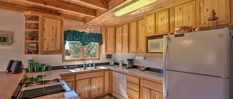 Una cocina con armarios de madera, un refrigerador blanco, una estufa y una ventana con un adornado verde.