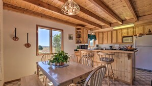 A wooden interior with a dining table, chairs, a potted plant, and a kitchen area with wooden cabinets and appliances. - Questa Home w/ Views - 13 Mi to Red River Skiing! (Questa)