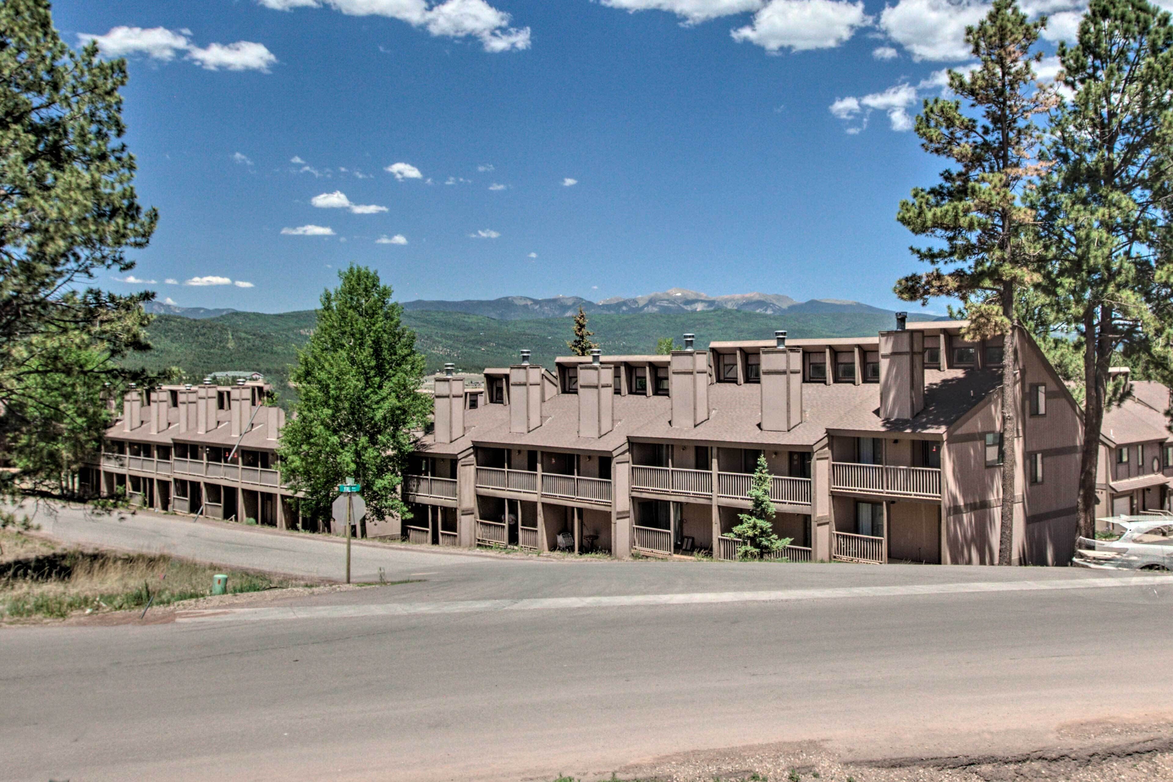 A multi-story building with balconies and a view of mountains in the background.