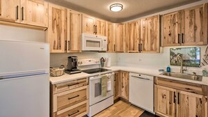 Une cuisine avec des meubles de rangement en bois, un réfrigérateur blanc, un four à micro-ondes, un four traditionnel et un lave-vaisselle.