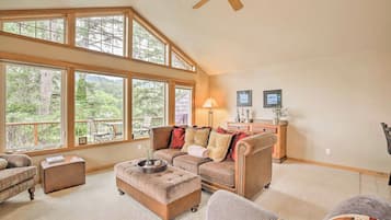 A spacious living room with large windows, a ceiling fan, and a cozy seating area.