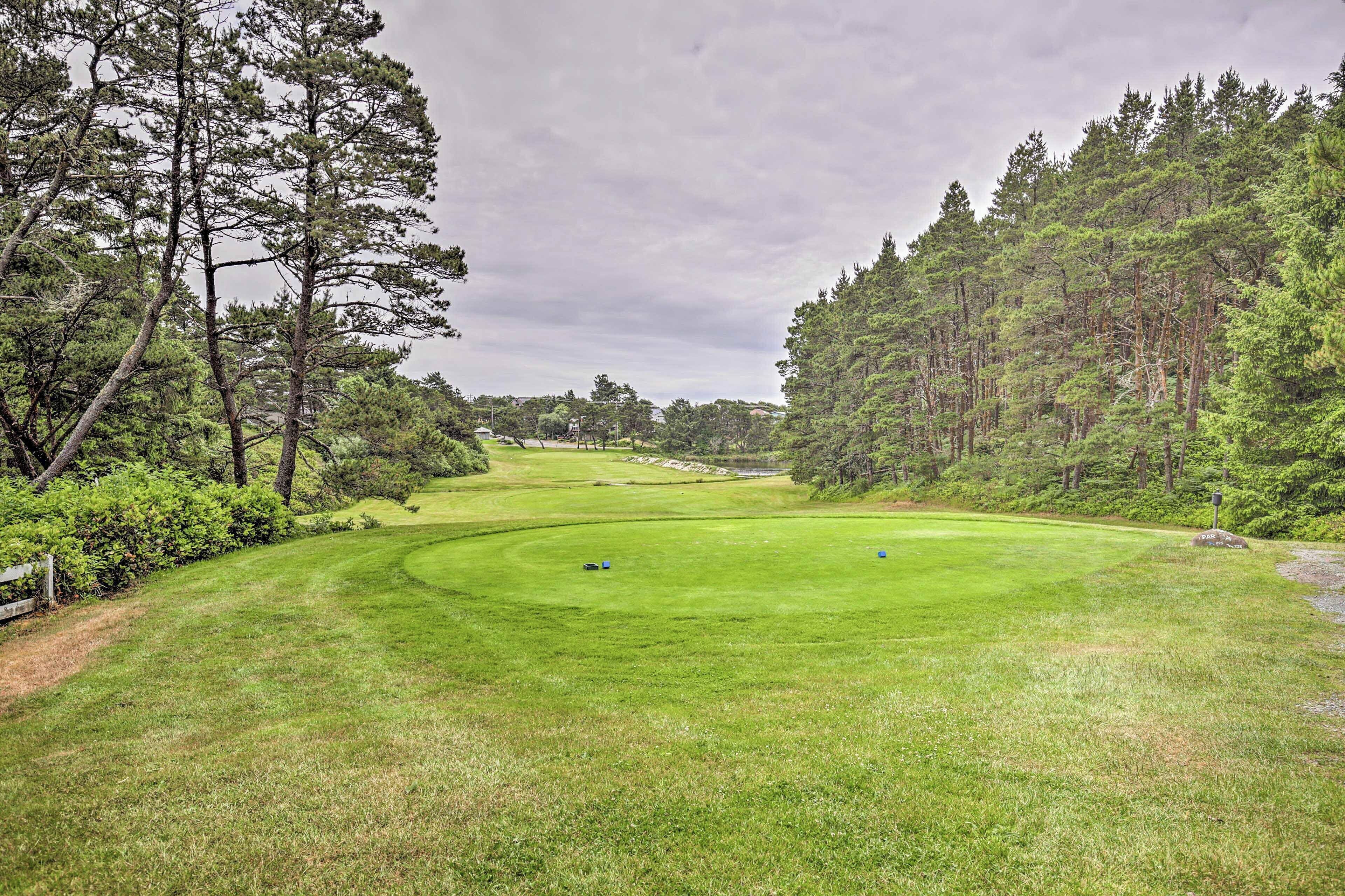 A golf course with a well-maintained fairway, surrounded by dense pine trees.