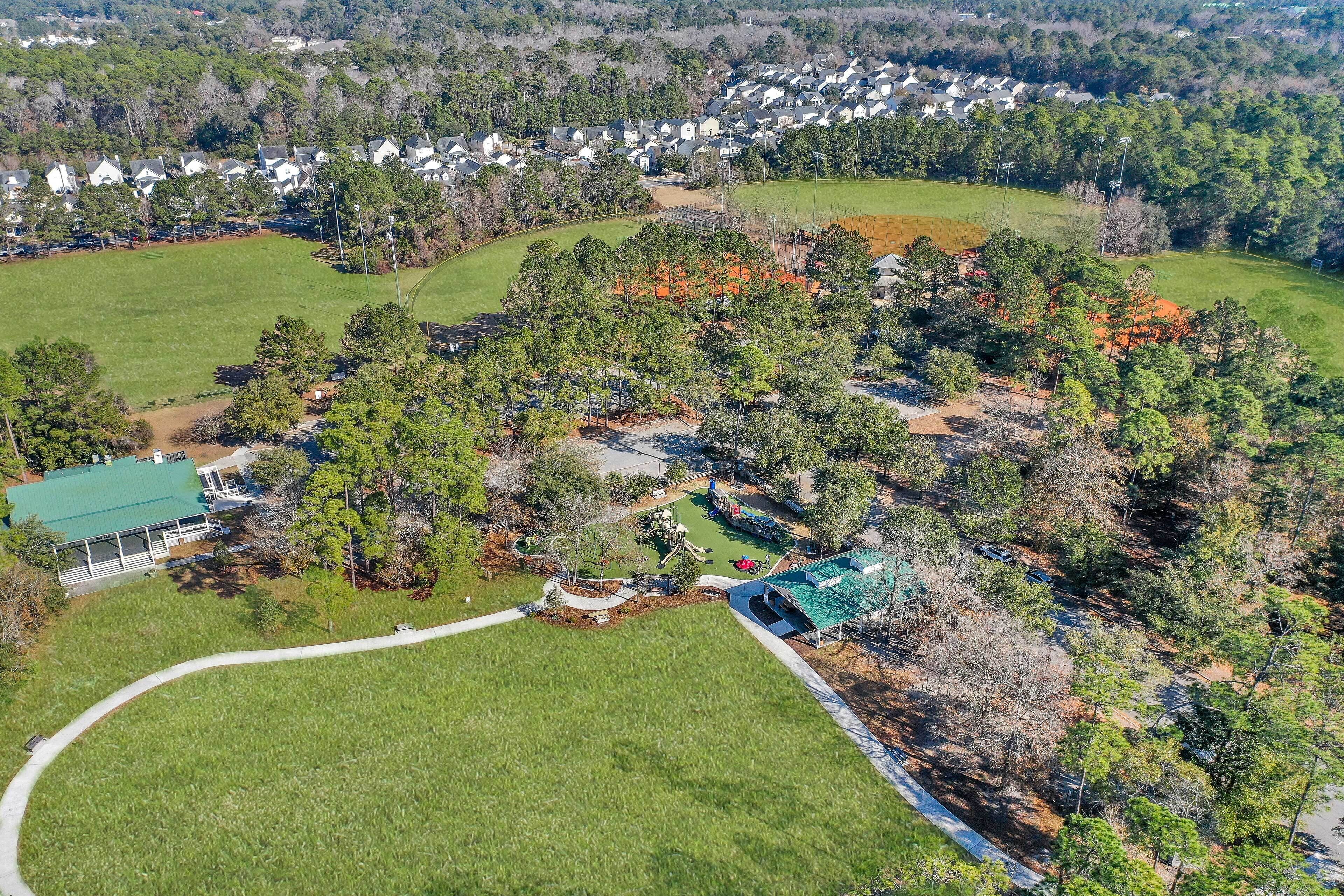 An aerial view of a residential area with houses, a large green field, and a playground.