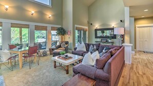 Un salon spacieux avec un haut plafond, de grandes fenêtres et un coin salon confortable avec un canapé et des fauteuils.