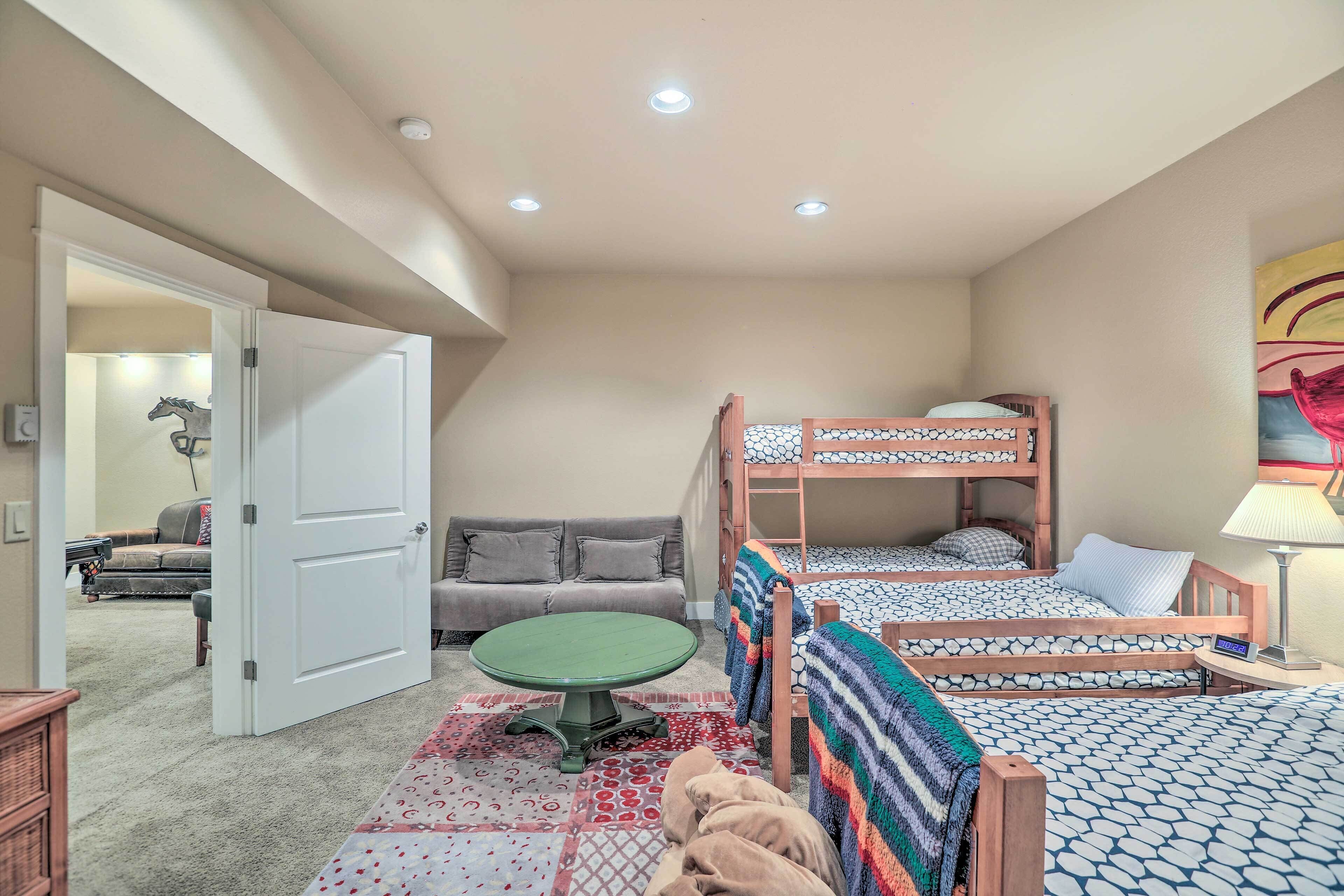 A bedroom with bunk beds, a green table, a sofa, and a lamp.