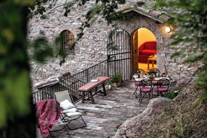 Ein Steinhaus mit einer Treppe, die zu einem Essbereich mit einem roten Sofa und einem Tisch für zwei Personen führt.