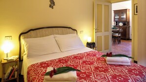 A neatly made bed with a patterned bedspread, a bedside lamp, and a small table with books. - Apartment with terrace (Rasiglia)