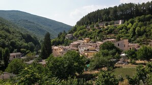 A hillside village with traditional buildings, surrounded by dense forest and hills. - Apartment with terrace (Rasiglia)