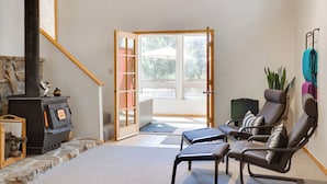Ein Wohnzimmer mit Kamin aus Stein, einer Couch und Blick durch eine Glastür auf eine Terrassenanlage.