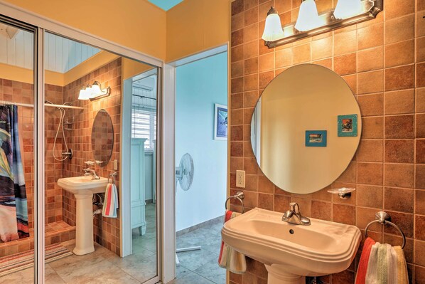 Une salle de bain avec un lavabo, un miroir et une douche.