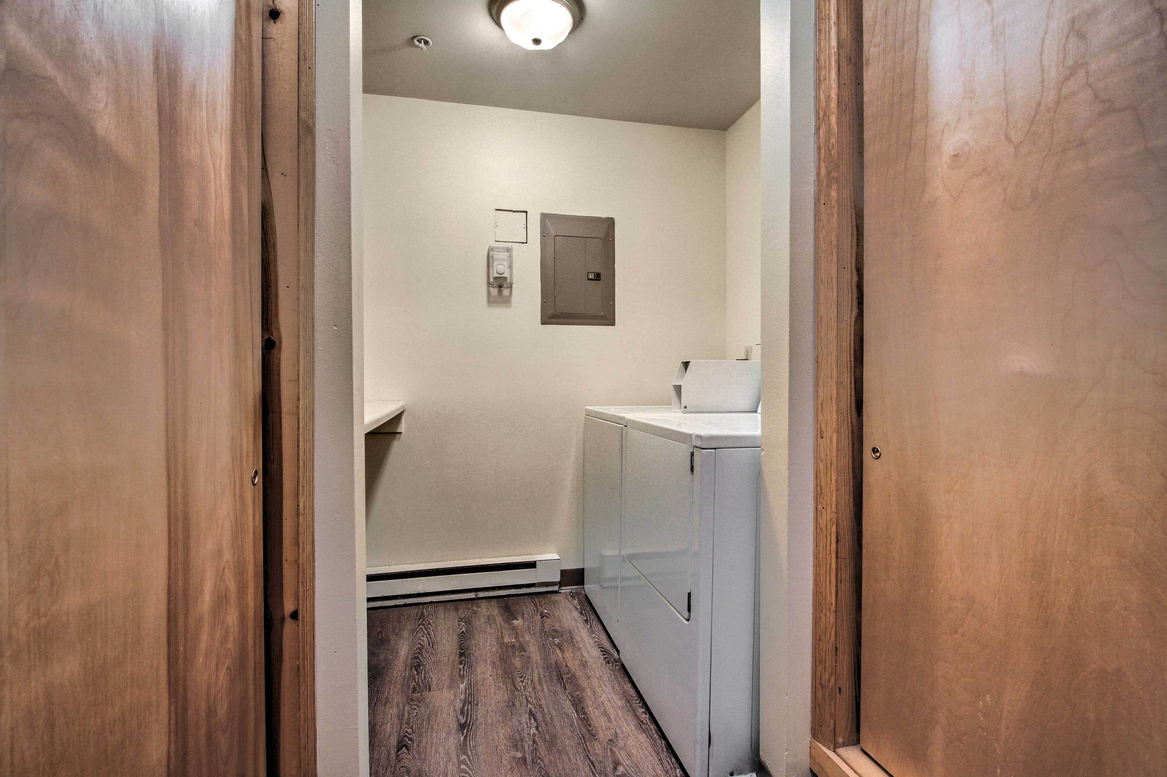 Un couloir étroit avec un plancher en bois, un lave-linge blanc et un petit évier.