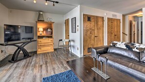 A modern living room with a flat-screen TV, wooden cabinets, a leather sofa, and a dining area with a table and chairs. - Pagosa Springs Condo w/ Patio, 4 Mi to Hot Springs (Pagosa Springs)