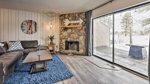 A modern living room with a stone fireplace, a large window, and a cozy seating area. - Pagosa Springs Condo w/ Patio, 4 Mi to Hot Springs (Pagosa Springs)