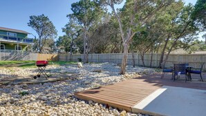 Un patio trasero con una terraza de madera, una parrilla y un área de estar con sillas.