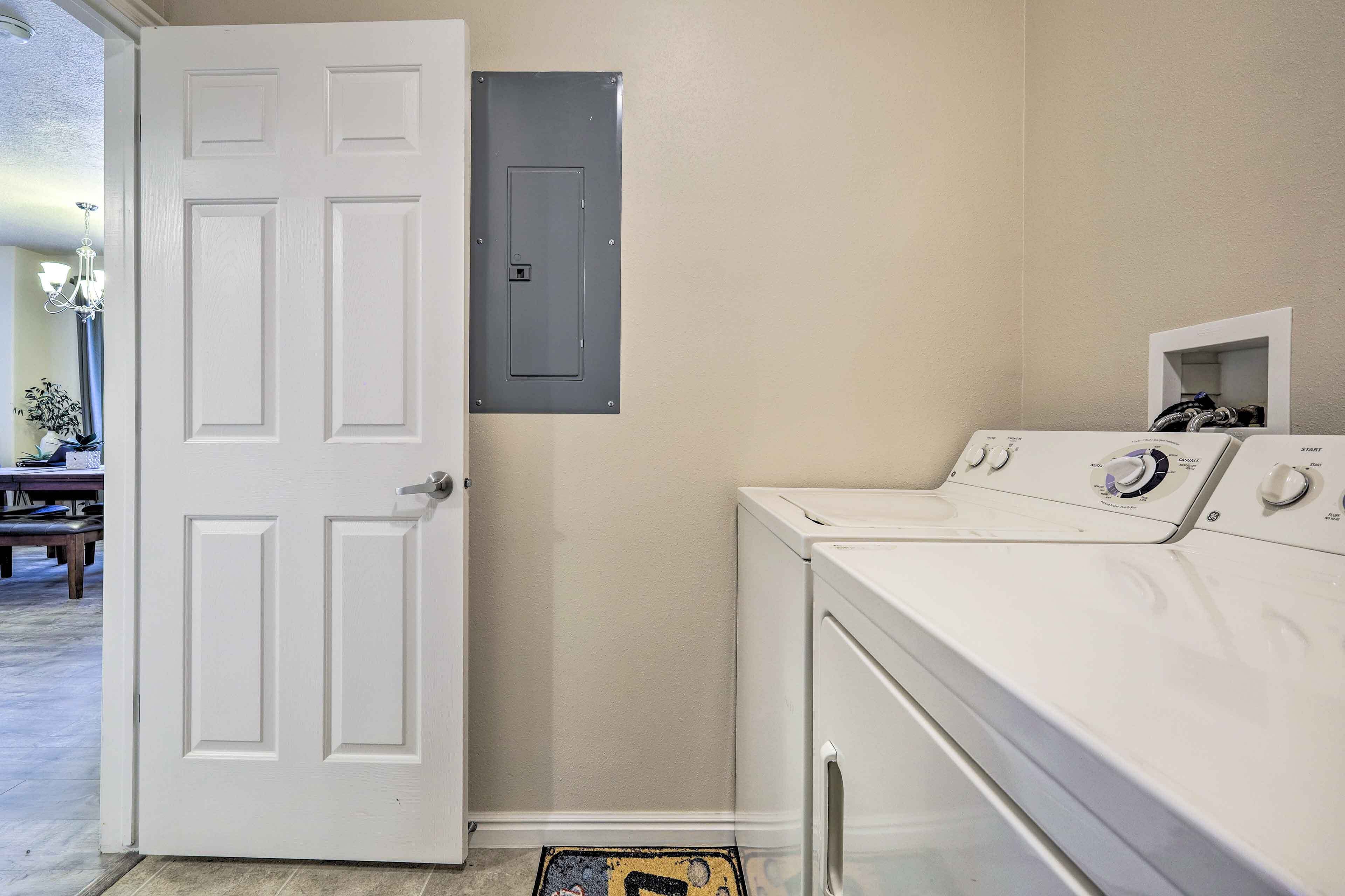 A laundry room with a white door, a washing machine, and a utility box on the wall.