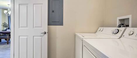 A laundry room with a white door, a washing machine, and a utility box on the wall.