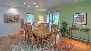 Uma sala de jantar com uma mesa e cadeiras de madeira, um vaso e um abajur.