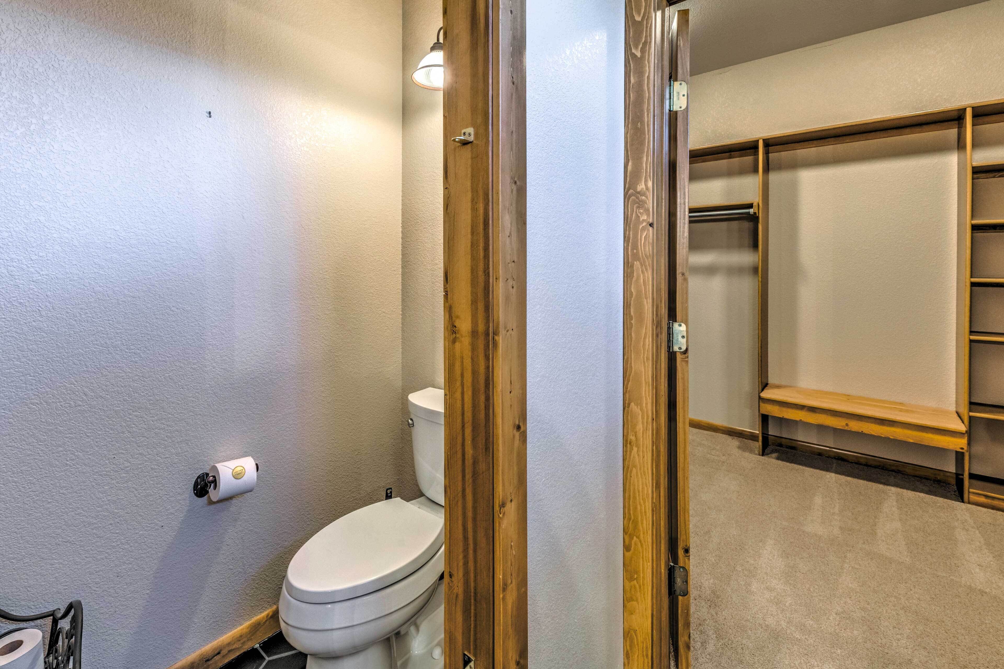 A bathroom with a toilet, a wooden door, and a shelf unit.