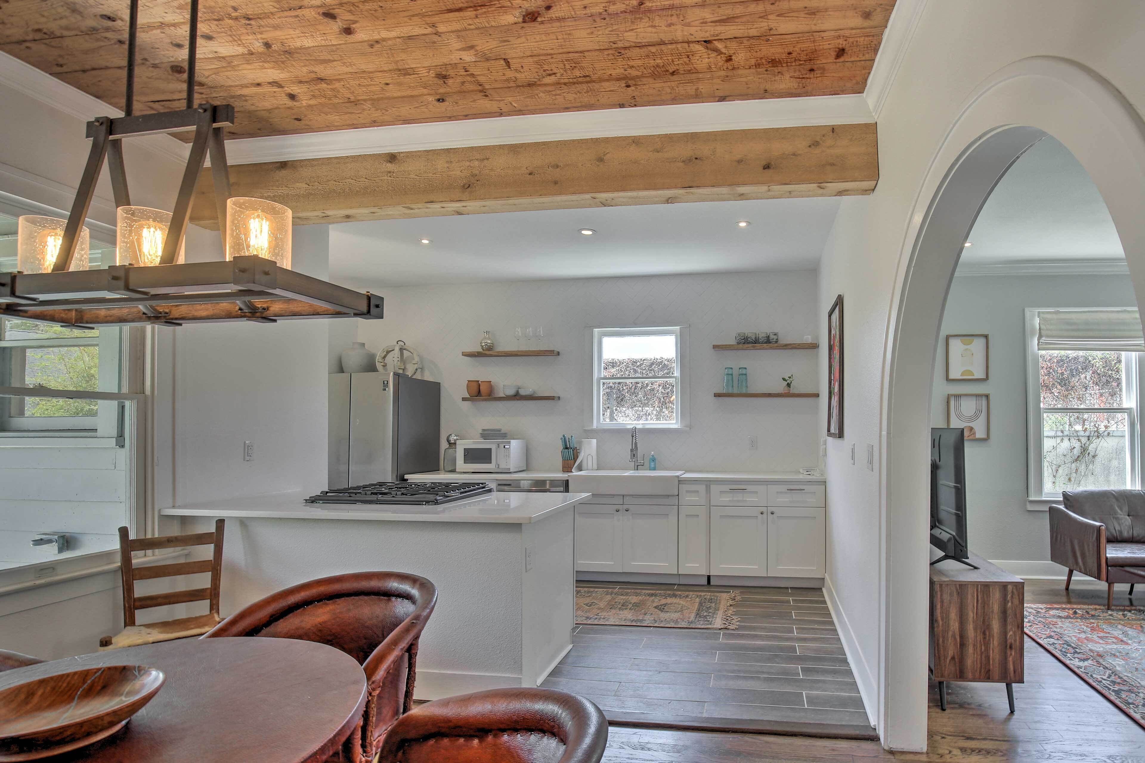 A modern kitchen with white cabinets, a central island, and a dining area with wooden chairs.