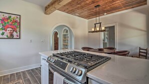 Une cuisine équipée d’une cuisinière à gaz, d’un four et d’un plan de travail en marbre. Le plafond est en bois et un tableau est accroché au mur.