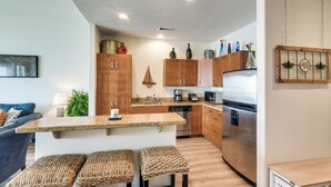 Eine moderne Küche mit Holzschränken, Edelstahlgeräten und einer zentralen Kochinsel mit gewebten Hocker.